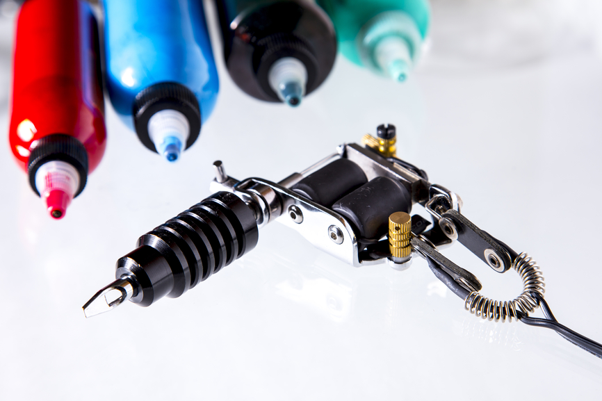 Tattoo gun with ink tubes on white background